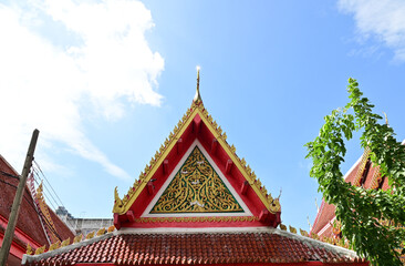 BANGKOK, THAILAND - June 20, 2023 : Part of the Roof of a temple in Thailand. Traditional Thai style pattern on the roof of a temple with Blue Sky Background.