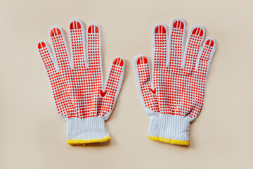 Red gardening gloves on a beige background. Top view, close-up.
