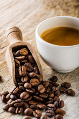 in the foreground a cup of espresso and coffee beans on a rustic wooden in the foreground a cup of...