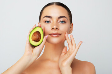 Beauty portrait of young topless woman showing halved avocado