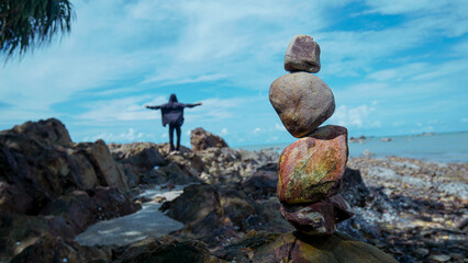 Rock balance on the beach, shot of sunny clouds. Zen meditation and relaxation