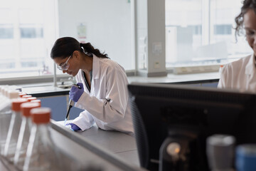 Female science student pipetting in laboratory 