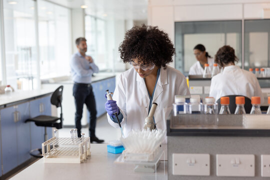 Female scientist pipetting in laboratory  - Powered by Adobe