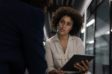 Businesswoman working late in an office with a colleague using a digital tablet