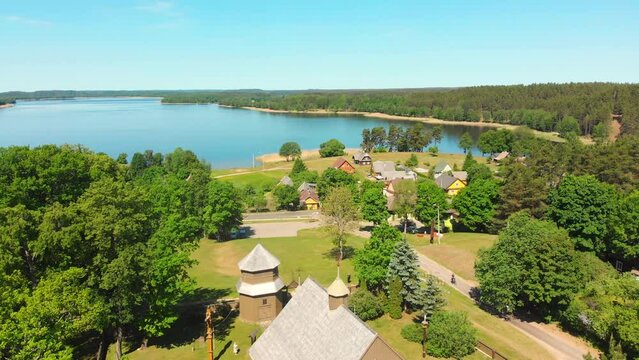 Aerial fly over beautiful iconic St.Joseph wooden stave church with no nails in famous Lithuania countryside holiday Village Paluse with Lusiai lake panorama in summer