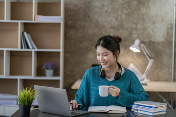 Asian female high school student learning and watching online course on laptop at home. Young female student studying in online classroom with teacher at home