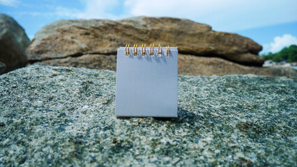 Mockup business paper card on beach rocks with stone texture background.