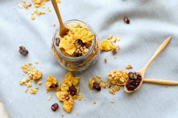 glass jar with homemade granola, nuts, pineapple and  berries