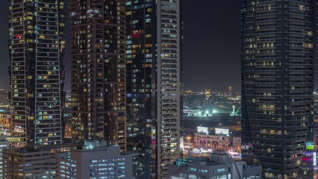 Business bay district skyline with modern architecture timelapse night from above. Aerial view of Dubai skyscrapers and illuminated towers near main highway. Multi-storey parkings and light in windows