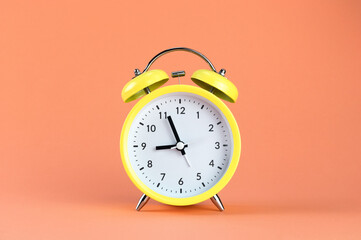 Yellow alarm clock on a colored orange background. Minimalism. Concept of time, planning.