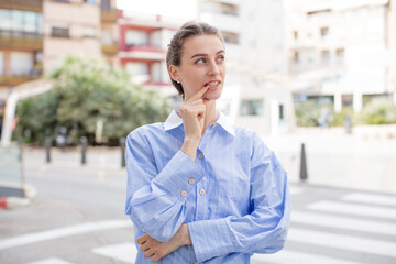 pretty woman with surprised, nervous, worried or frightened look, looking to the side towards copy space