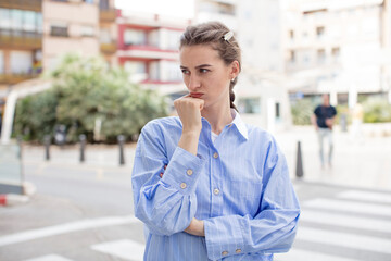 Fototapeta premium pretty woman feeling serious, thoughtful and concerned, staring sideways with hand pressed against chin