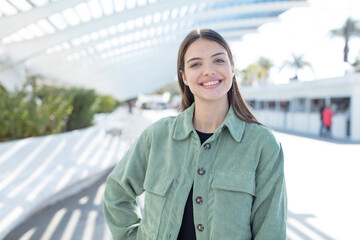 young pretty woman smiling happily with a hand on hip and confident, positive, proud and friendly...