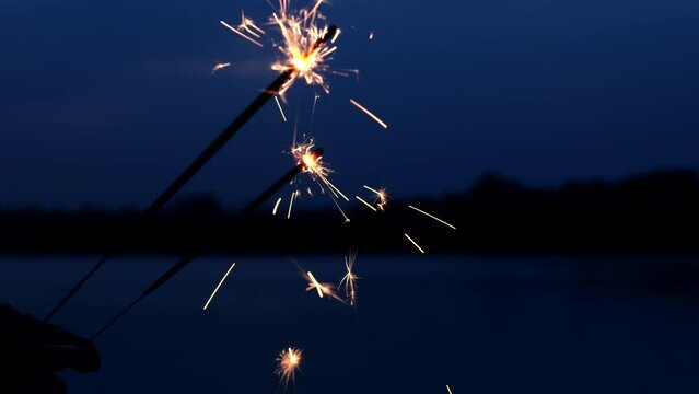 Hand holding sparklers fireworks celebration fourth of July, USA Independence Day July 4th on outdoor sunset background. Concept 4th of July, Holiday, USA, Freedom, Juneteenth, Memorial, Veterans, Day