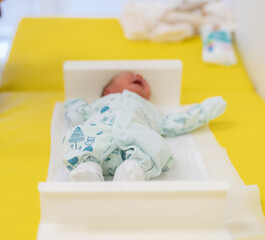 Little newborn lying. Small newborn feet in hands.