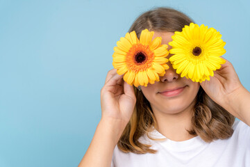 large portrait of funny teenage girl with gerbera flowers in her eyes