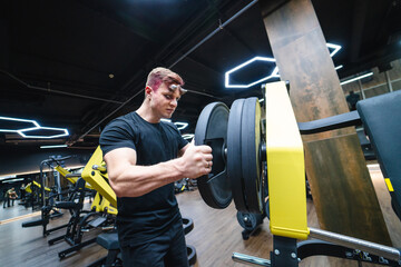 Obraz premium Young handsome man training in the gym. Sporty lifestyle male working out.