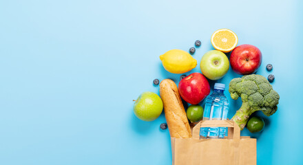 Shopping paper bag full of healthy food on blue