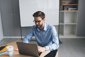 Millennial businessman working on laptop in office