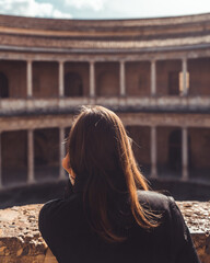 A woman ponders Carlos V's palace, captivated by its grandeur and historical significance, immersed in contemplation.