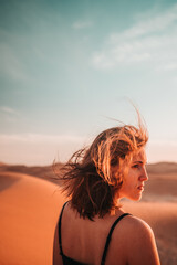 Desert portrait: A woman's hair dances with the wind, embodying untamed beauty and a sense of enchantment amidst the barren expanse.