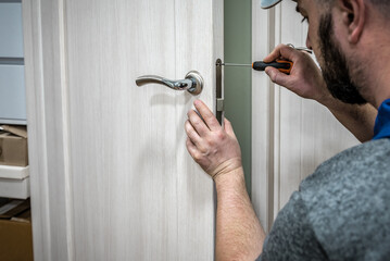 Locksmith instaling new lock in the door