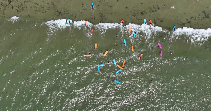 Magnified top view of the beach with a surf school practising on the waves by the beach 4k