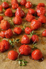 Strawberries drizzled with honey, thyme sprigs, on parchment-lined baking sheet.