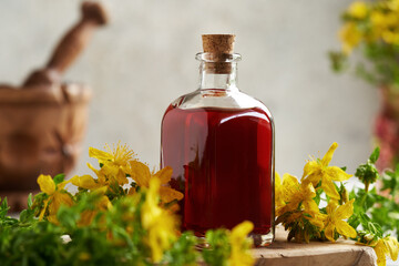 A glass bottle of St. John's wort oil with fresh flowers