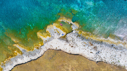 Aerial view on boat on blue Mediterranean sea at sunny day. View from the air on the waves and rocks. Sea relaxation and travel. A bright sunny day during a summer vacation. Top view from drone.