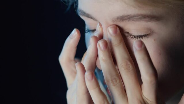 Close up of exhausted woman sitting in front of computer touching her eyes and face with fingers and heavily sighing