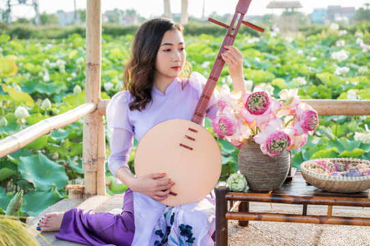 Vietnamese woman wearing traditional dress (ao dai) in a lotus flower pond