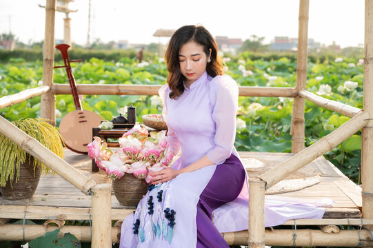 Vietnamese woman wearing traditional dress (ao dai) in a lotus flower pond