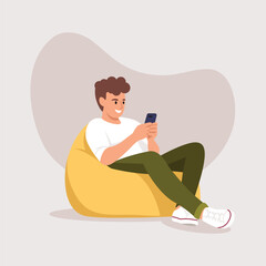 man (boy) sitting in a bag chair with a phone