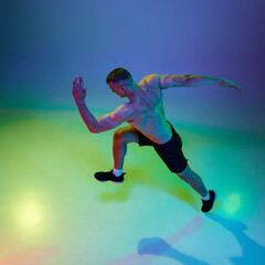 Fototapeta na wymiar Sport achievements. Top view image of man, professional runner, athlete in motion against gradient studio background in neon light