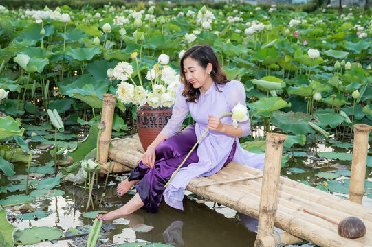 Vietnamese woman wearing traditional dress (ao dai) in a lotus flower pond