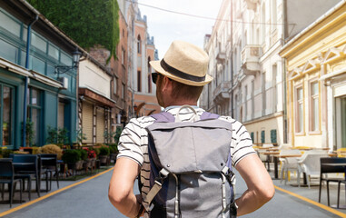 Man with backpack walking down street in European city. © Barillo Images