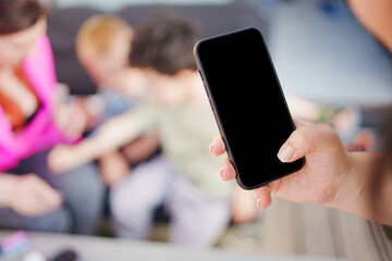 A smartphone with a black screen in a hand against the people out-of-focus 