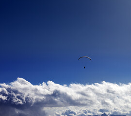 Silhouette of paraglider and blue sunny sky