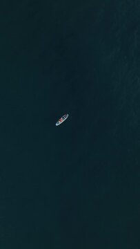 Vertical Video: SUP Sunset Romance - Aerial Perspective of Sporty Couple Embracing the Sea