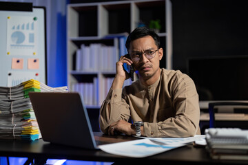 Plakat Overworked young Asian office employee working on laptop computer overtime in office at night