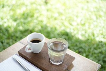 Hot coffee and glass of ice on wooden tray with plant pot