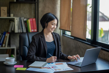 Happy young asian businessman sitting on her desk in the office Young woman working on laptop.
