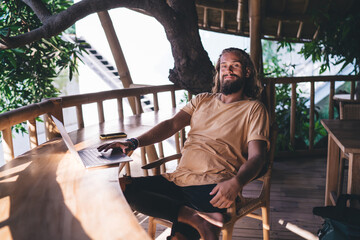 Portrait of bearded freelance copywriter posing at terrace during time for doing remote work on laptop technology, Caucaisan IT professional with netbook computer enjoying digital nomad lifestyle