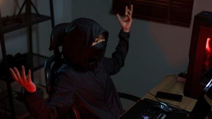 Hacker in hoodie raising hands while having problem with hacking programming system or server