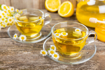 Chamomile herbal tea in a glass cup on a brown wooden table with honey, lemon and chamomile bouquet. Close-up. Copy space. healthy herbal drinks, immunity tea. Natural healer concept.Place for text.