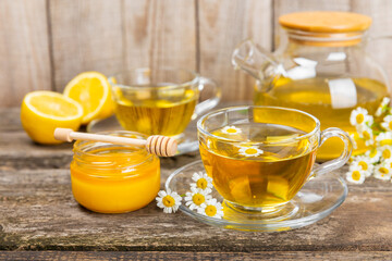 Chamomile herbal tea in a glass cup on a brown wooden table with honey, lemon and chamomile bouquet. Close-up. Copy space. healthy herbal drinks, immunity tea. Natural healer concept.Place for text.