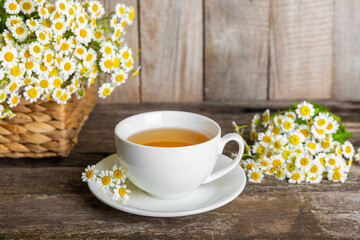 Herbal chamomile tea in a cup on a brown wooden table with honey, lemon and chamomile bouquet. Close-up. Copy space. healthy herbal drinks, immunity tea. Natural healer concept.Place for text.