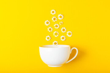 A cup of chamomile tea with chamomile flowers on a yellow background. Close-up. Copy space. healthy herbal drinks, immunity tea. Natural healer concept.Place for text.