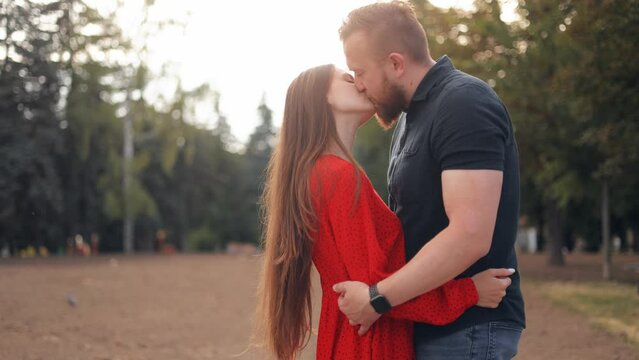 Portrait of love couple kissing on city street. Affectionate man circling woman in arms outdoor in slow motion. Young lovers feeling happy during romantic date on urban background.